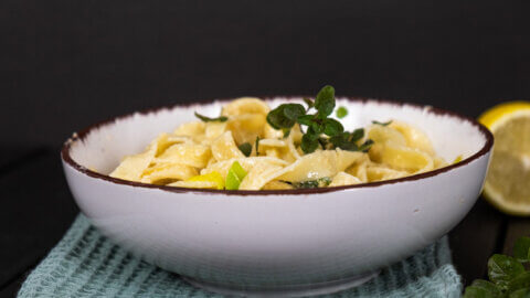 Creamy pasta in a white bowl on a black background.