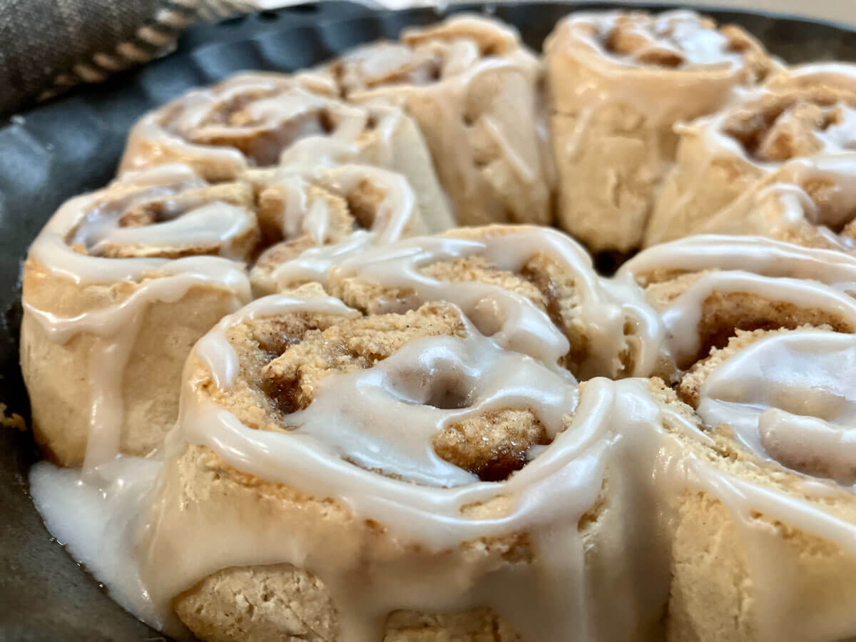 Gluten free cinnamon rolls, frosted in a cast iron pan.