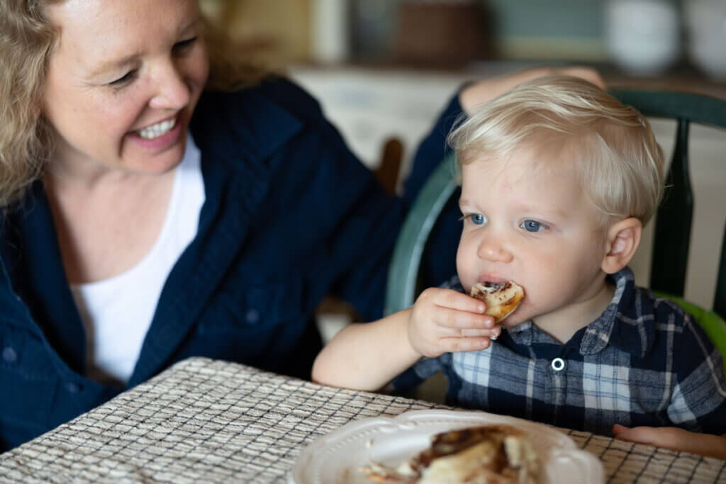 Toddler eating a gluten free cinnamon roll.