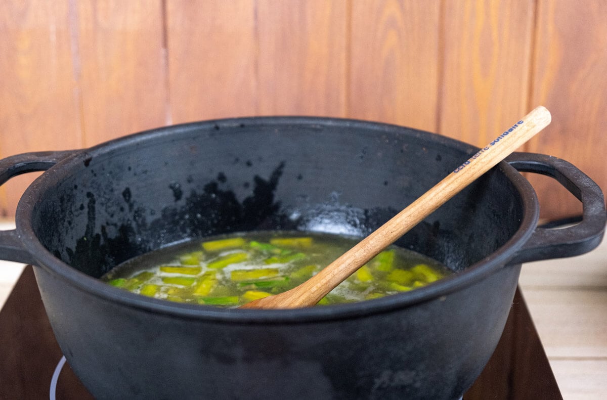 Asparagus cooking in broth a pot.