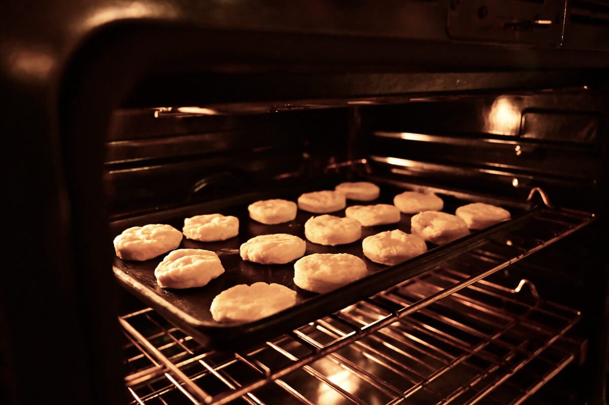 Biscuits on a cookie sheet being placed into an oven.