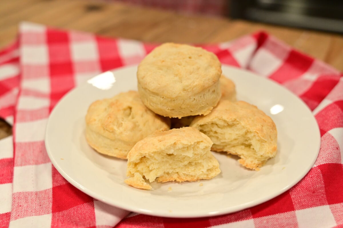 Homemade biscuits stacked up on a white plate.