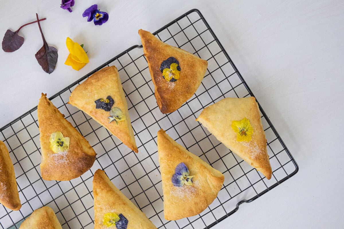 Scones with pansy flowers on top cooling on a wire rack.