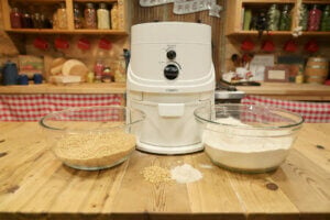 NutriMill Grain mill on a kitchen counter with two glass bowls of grain and flour.