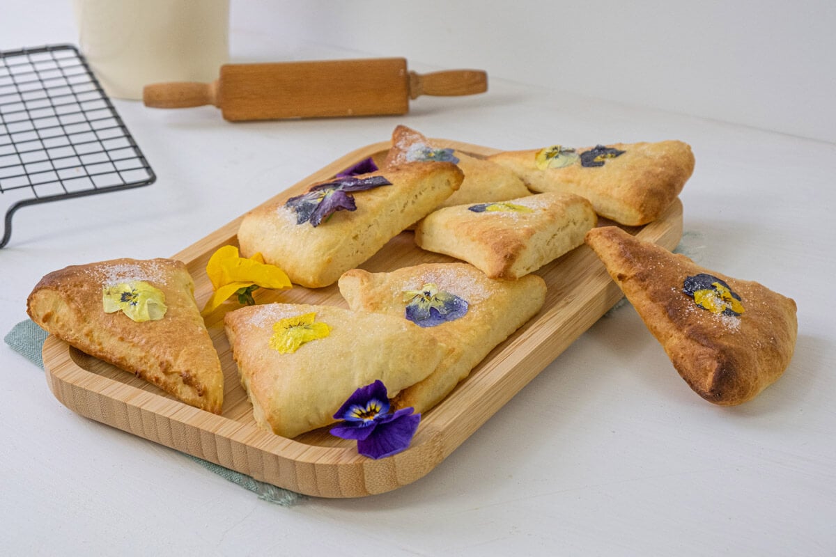 Whole wheat scones with pansy flowers stacked on a serving platter.