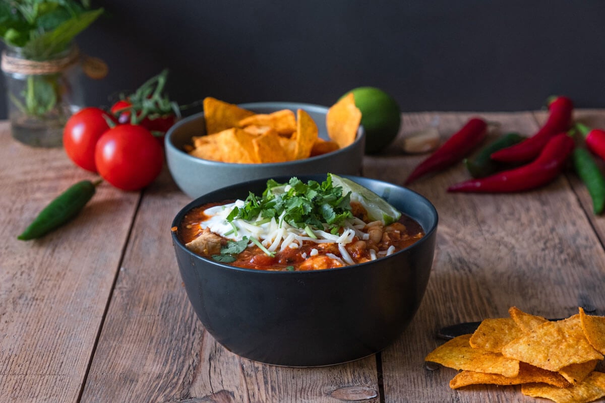 Chicken chili dished up in a black bowl.