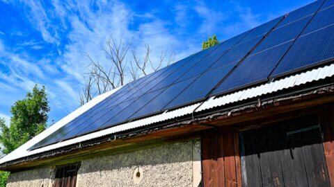 Solar panels on the roof of a large barn.