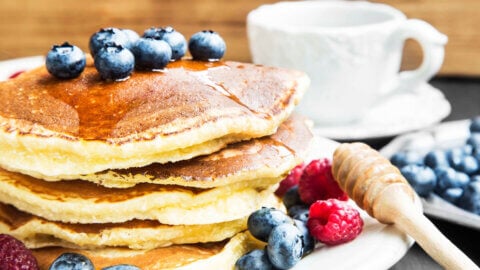 A stack of pancakes topped with syrup and fresh fruit.