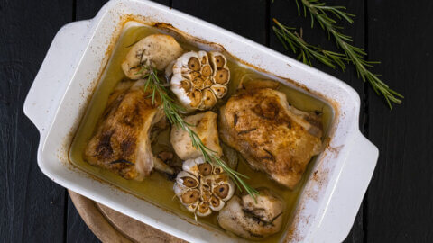 Roasted garlic chicken in a white baking dish.