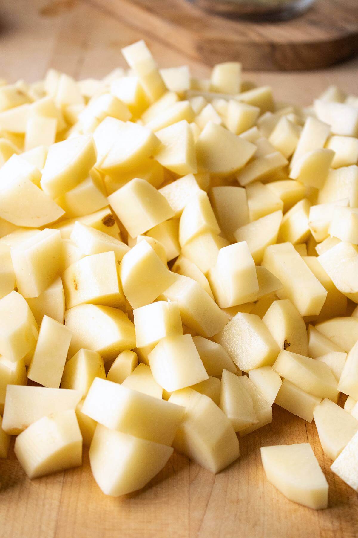 Close-up of peeled potato chunks on a wooden cutting board, ready for canning.