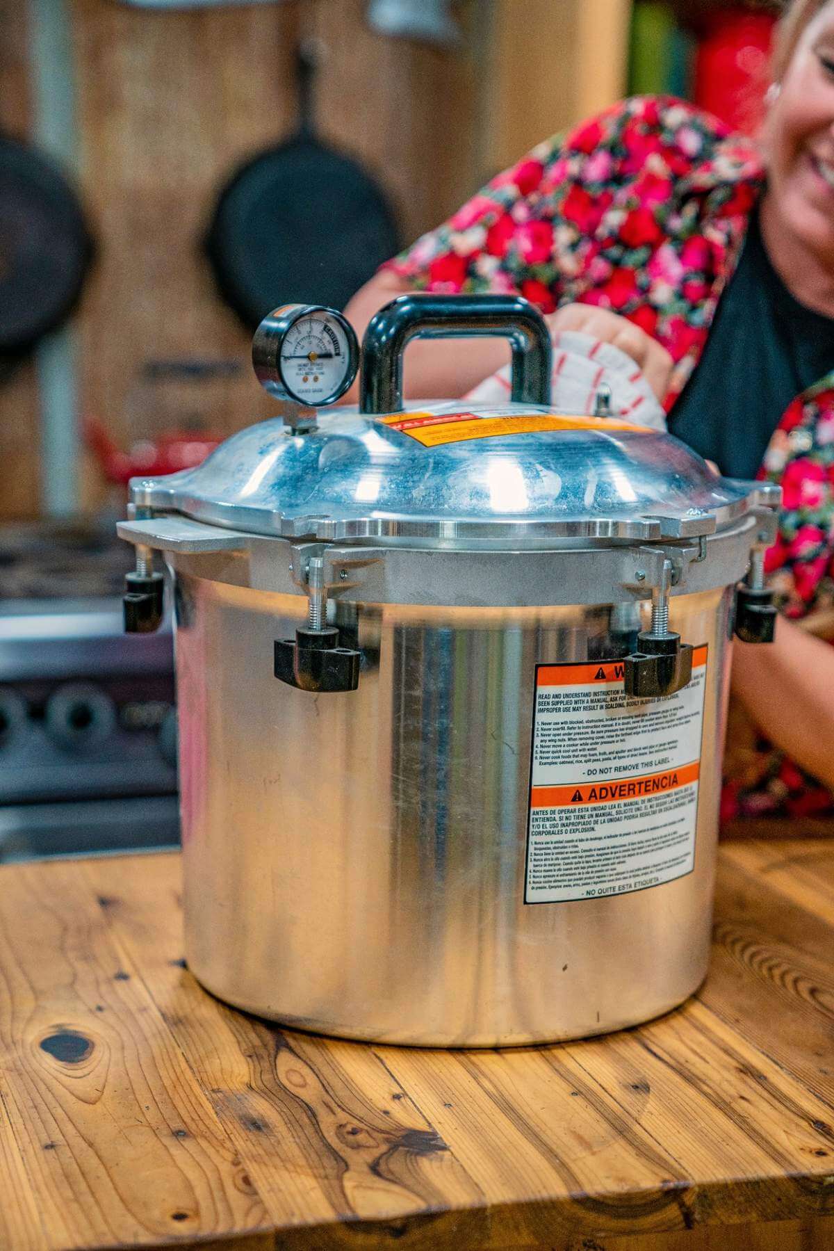 Pressure canner with a secured lid and dial gauge on a wooden kitchen counter.