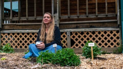 A woman sitting in the garden with a cup of coffee.