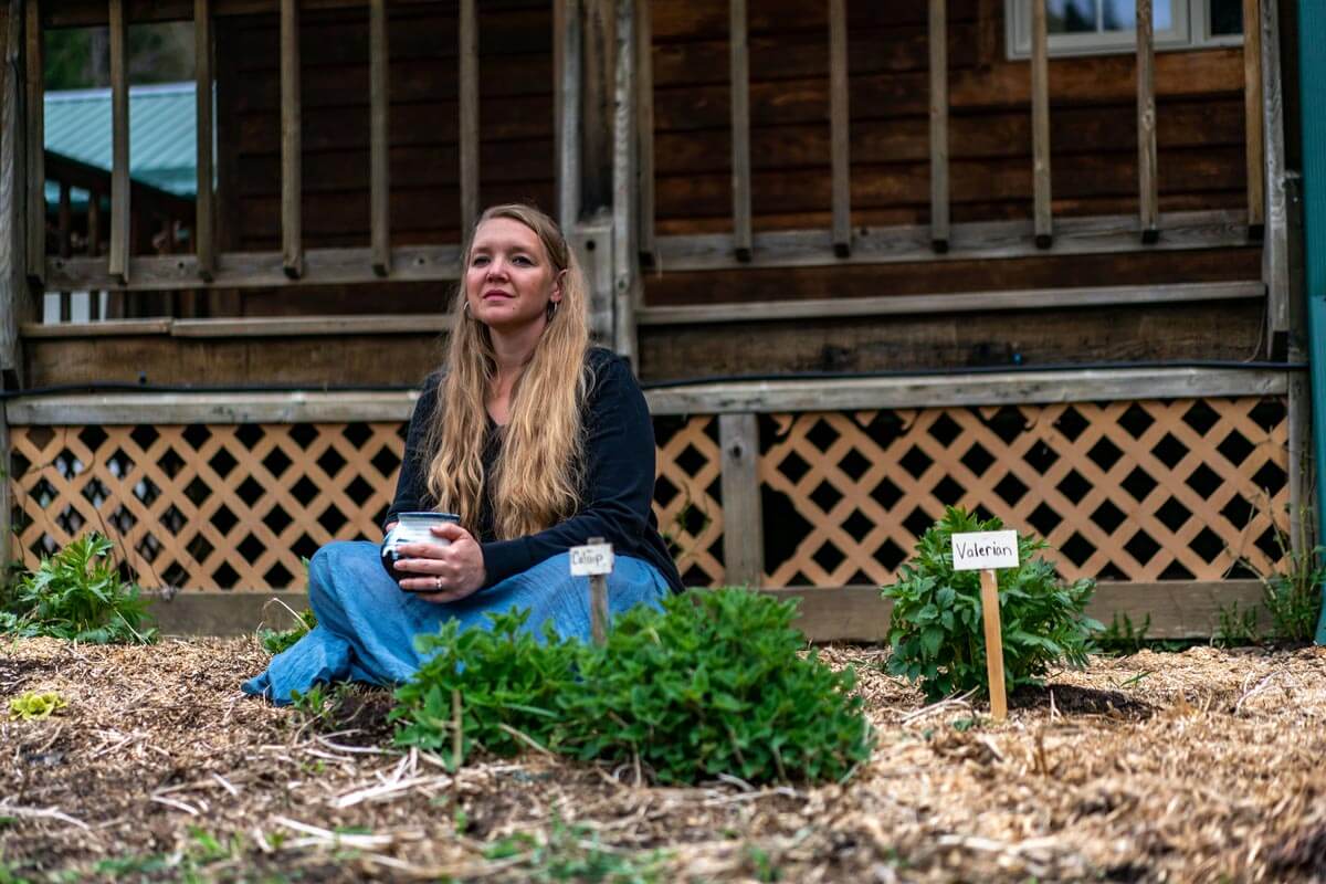 A woman sitting in the garden with a cup of coffee.