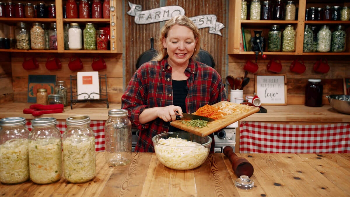 A woman adding ingredients to cabbage for homemade curtido.