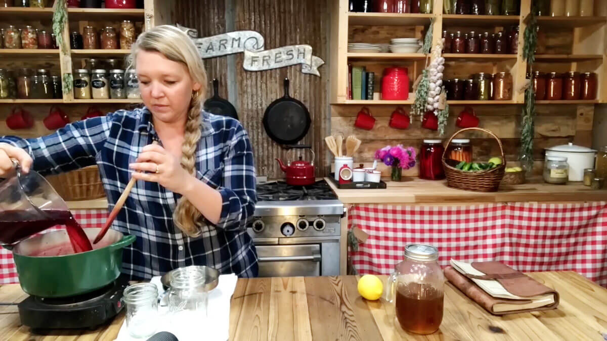 A woman pouring elderberry juice into a Dutch oven.