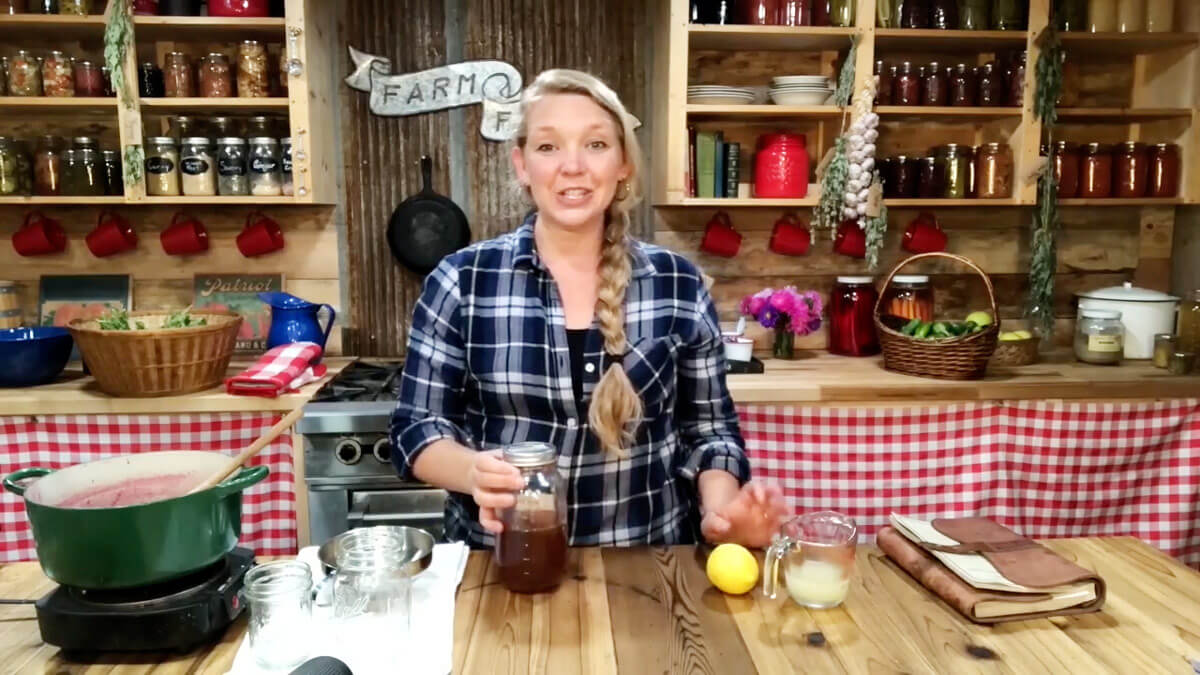 A woman holding a jar of freshly cooked elderberry syrup ready to cool.