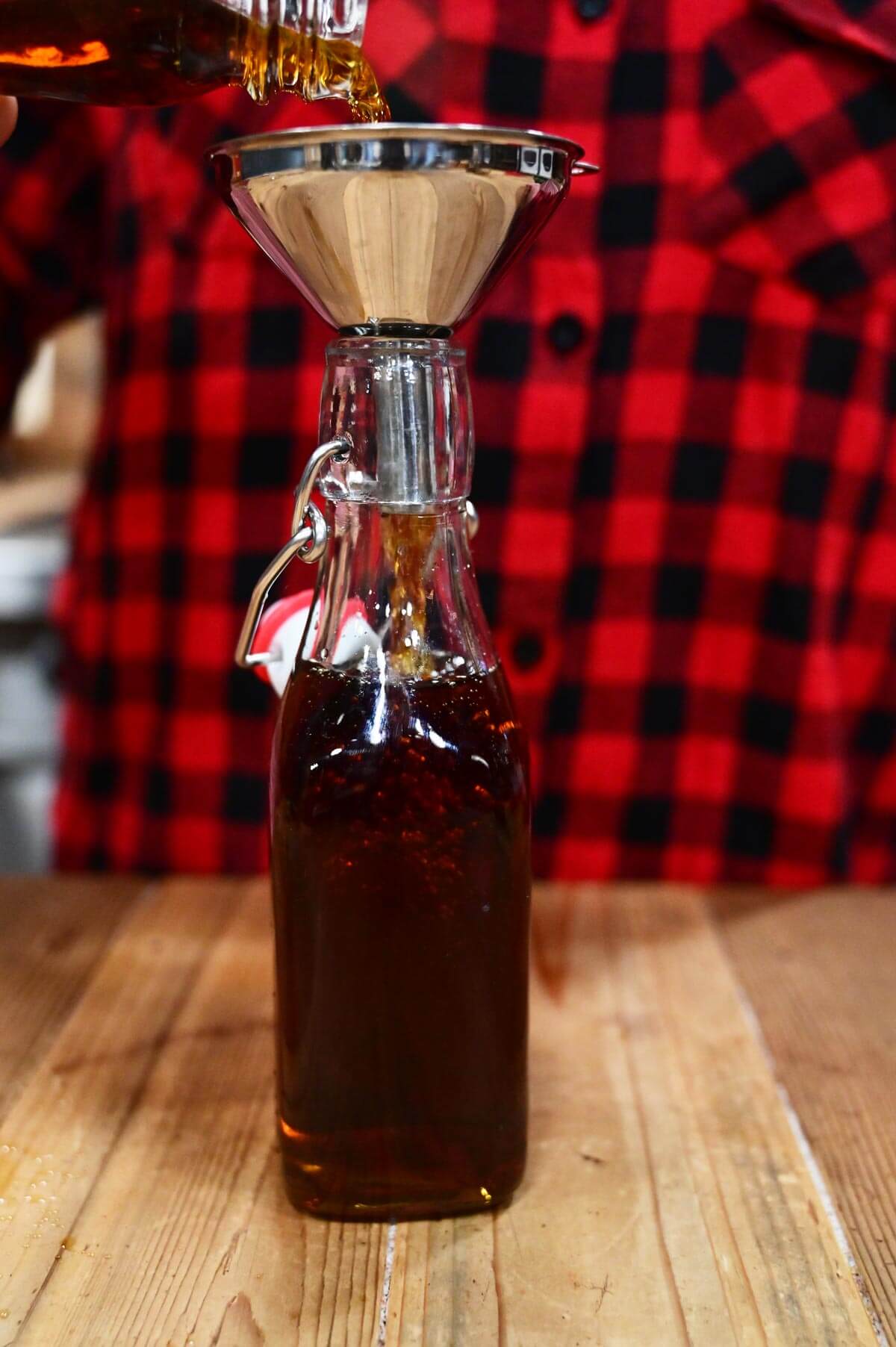 Vanilla extract being poured into a small flip top bottle.