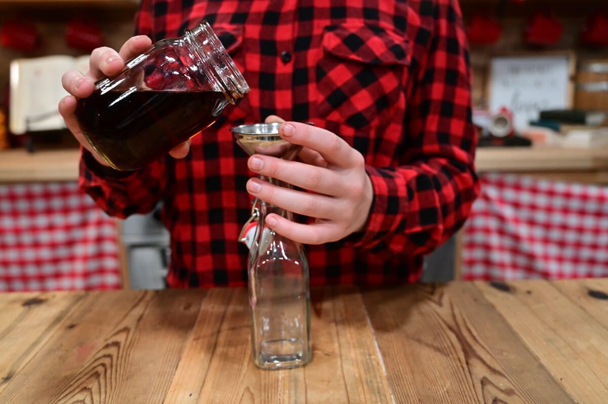 Vanilla extract being poured into a small flip top bottle.