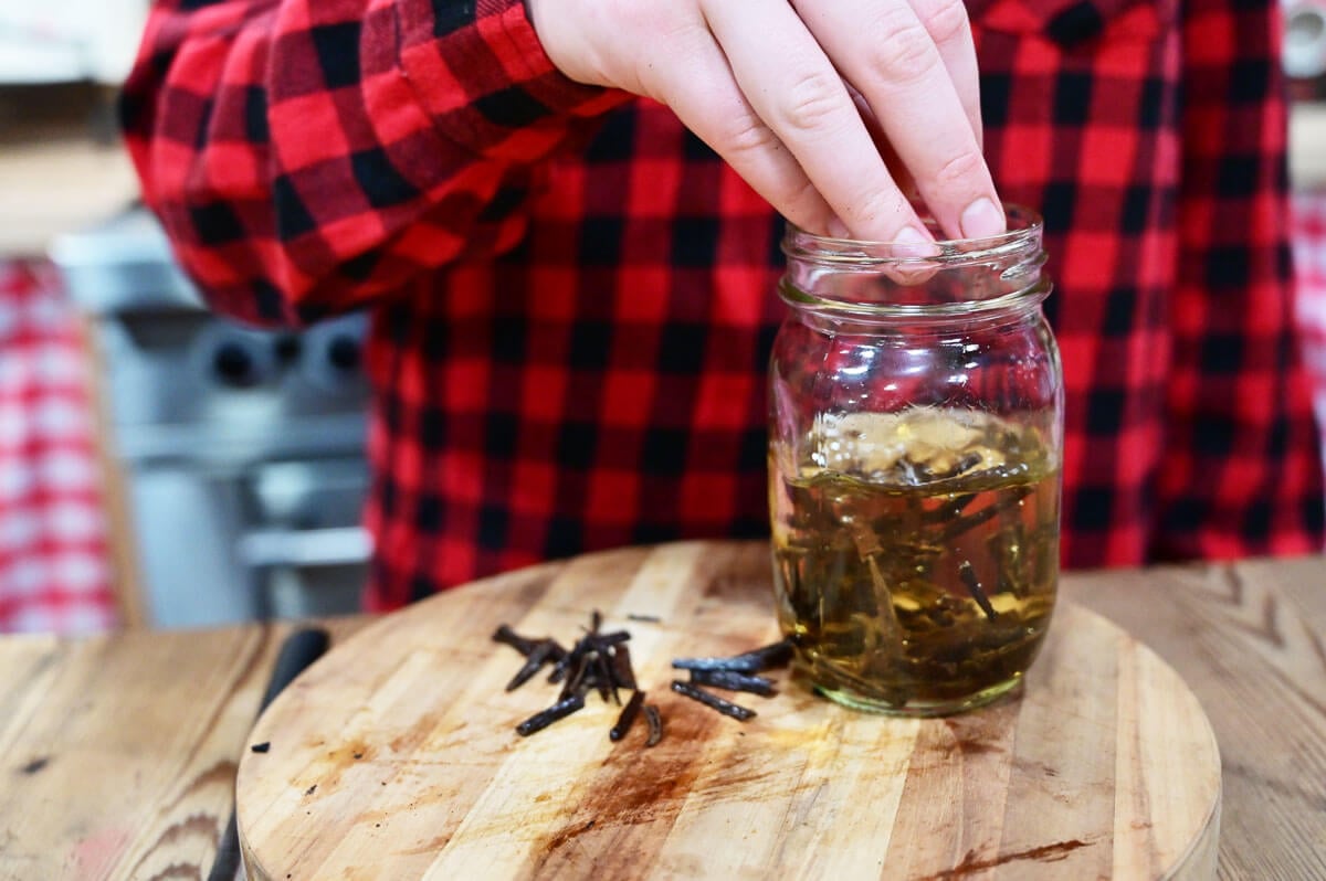 Vanilla beans being placed in a jar with alcohol to make homemade vanilla extract.
