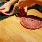 Ground Pork breakfast sausage being fed into pork casings.