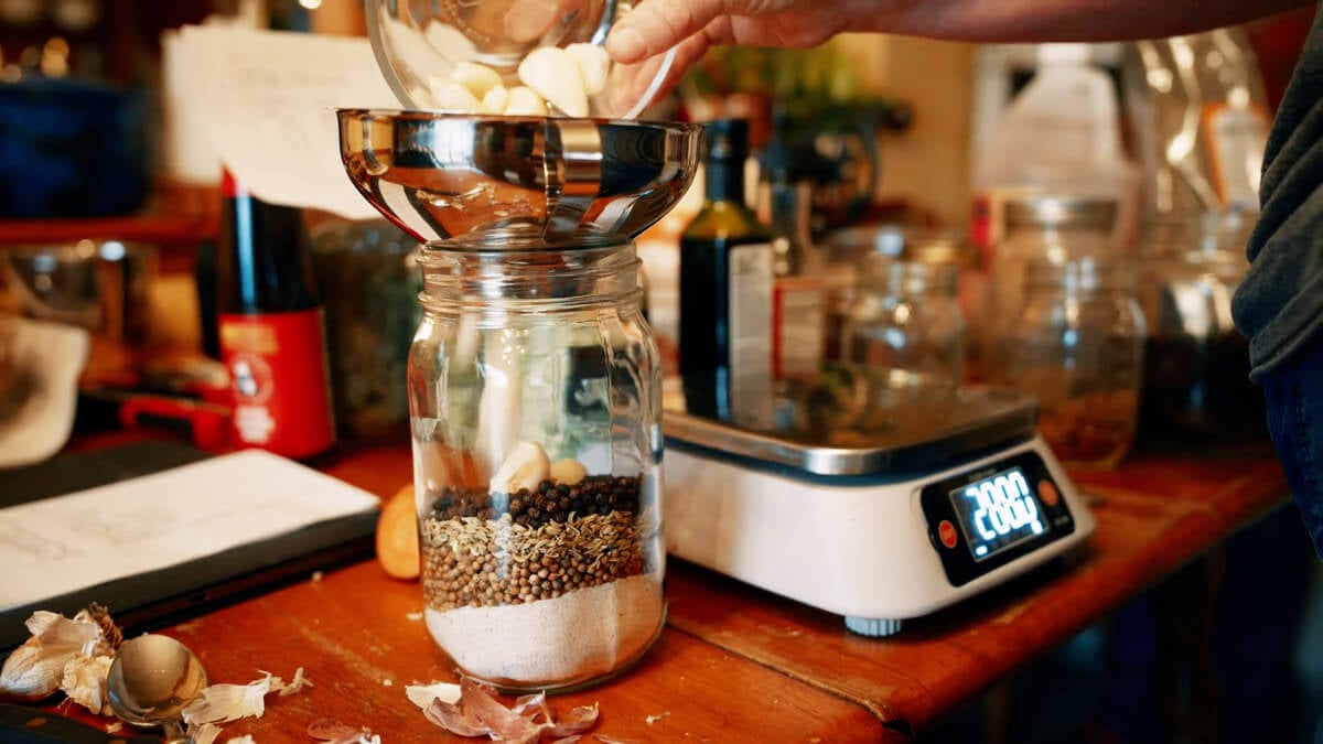 Pork sausage herbs and seasonings being mixed into a quart Mason jar.