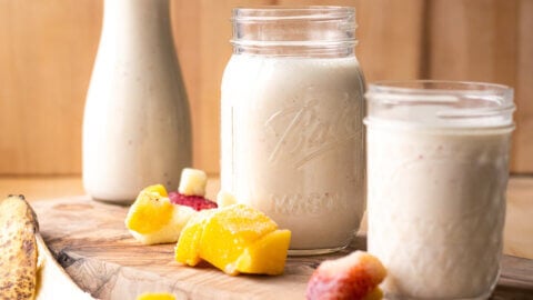 Milk kefir in a jar and a glass with fruit next to it.