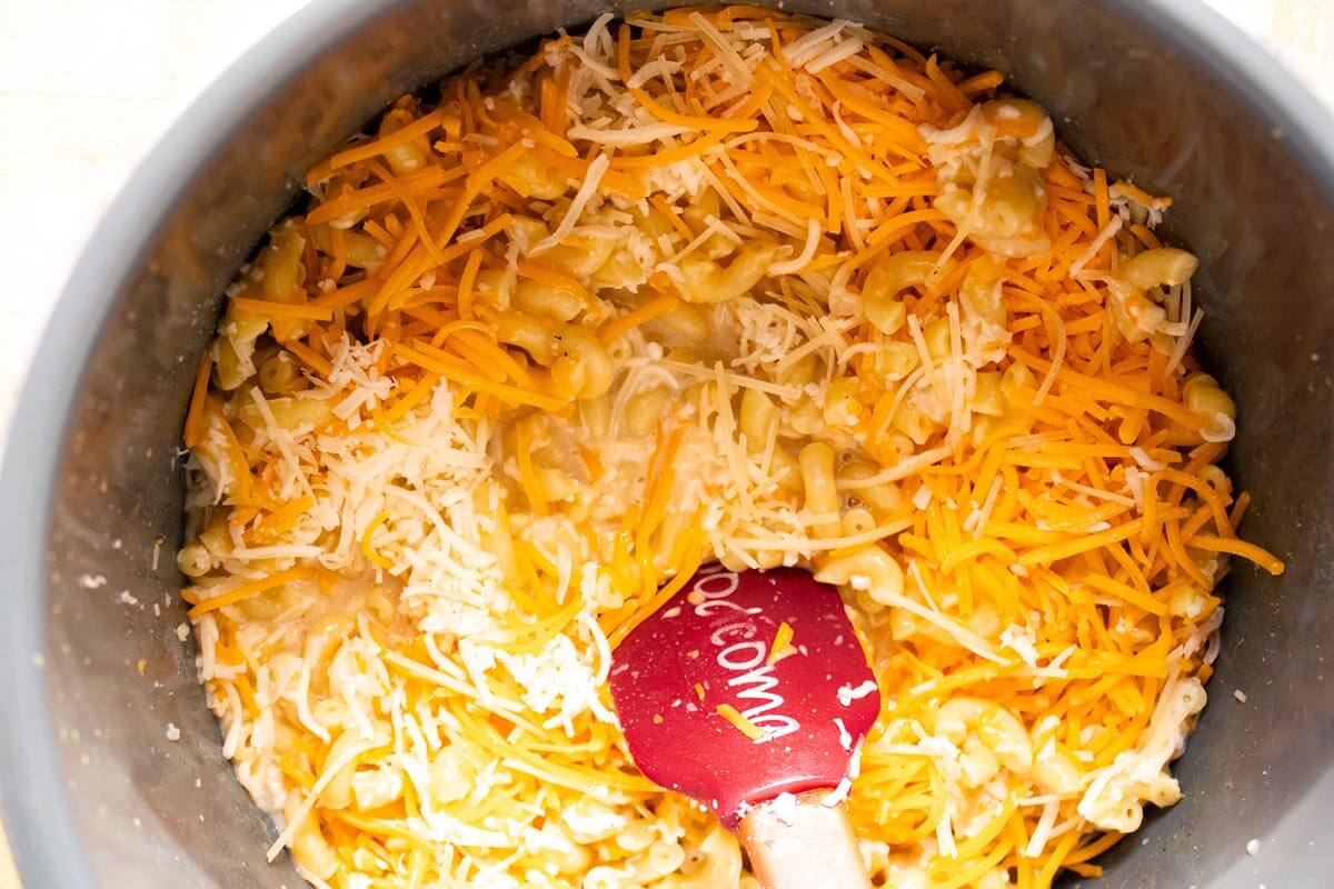 Cheese being stirred into cooked macaroni noodles.