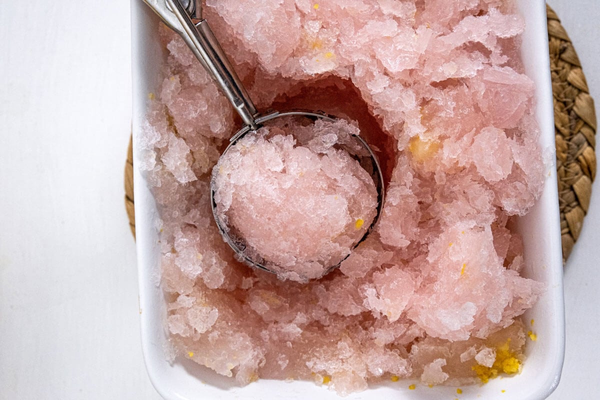 Lemon sorbet being scooped out of a pan.
