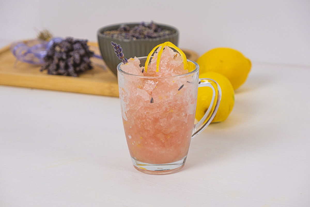 Lemon sorbet served in a glass with lemon zest and lavender on top.