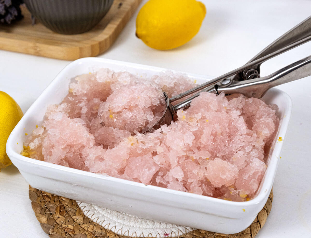 Lemon sorbet being scooped out of a pan.
