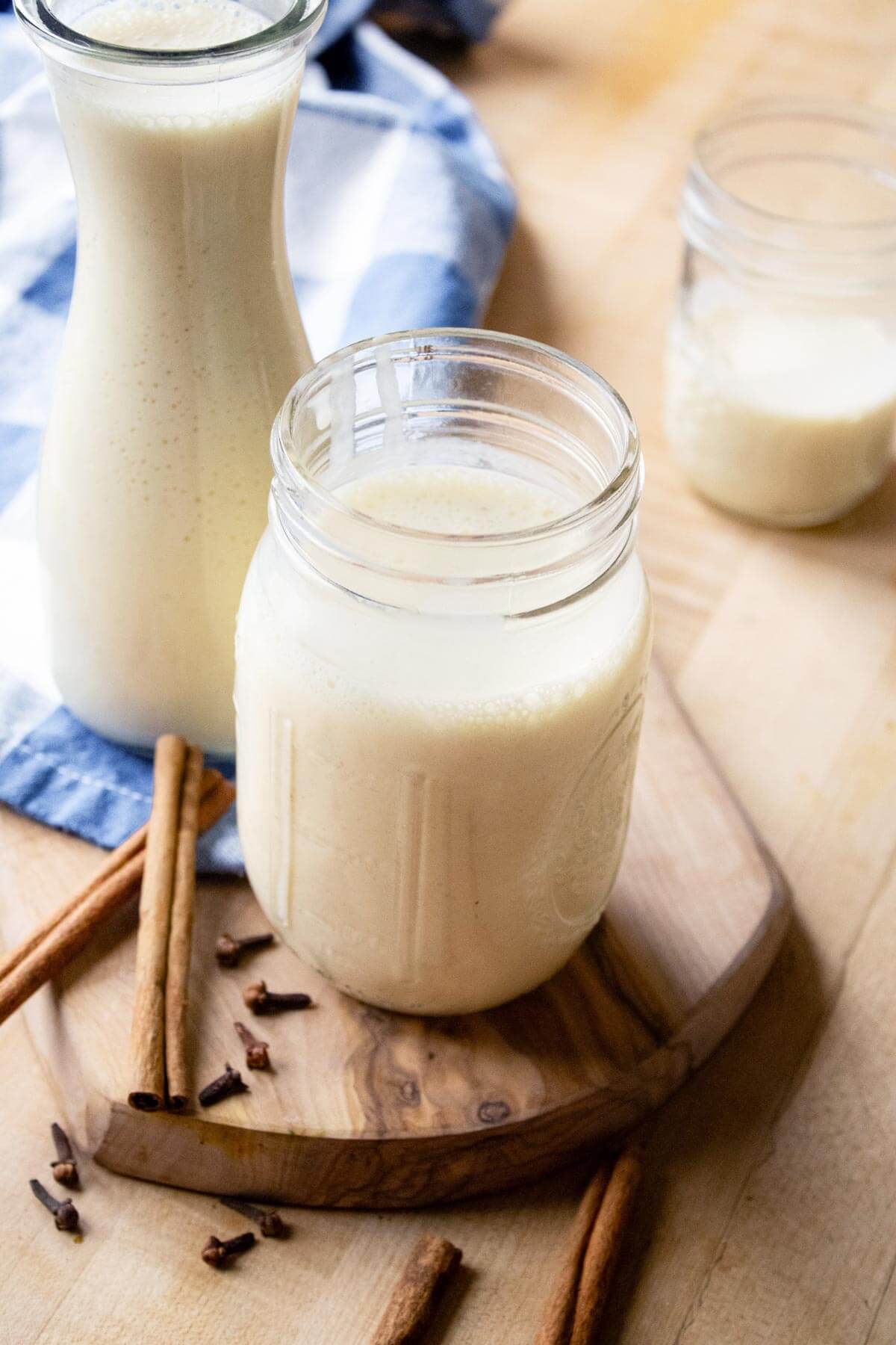 Milk kefir in a jar and a glass with a cinnamon stick next to it.