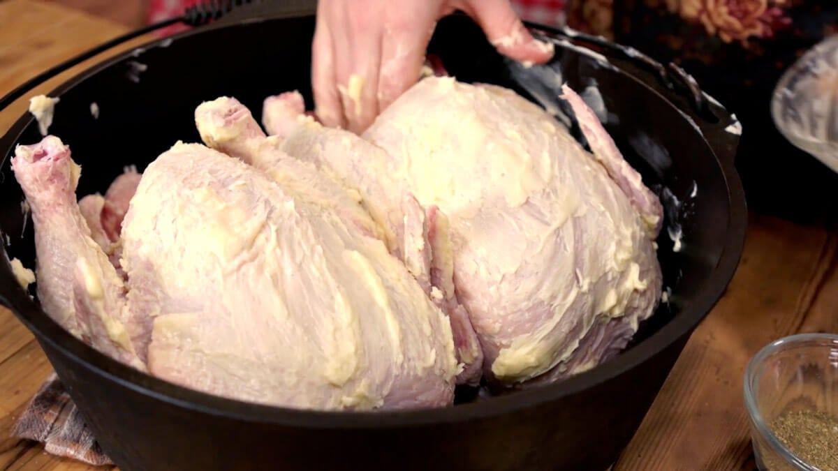 Two whole chickens getting coated in butter.