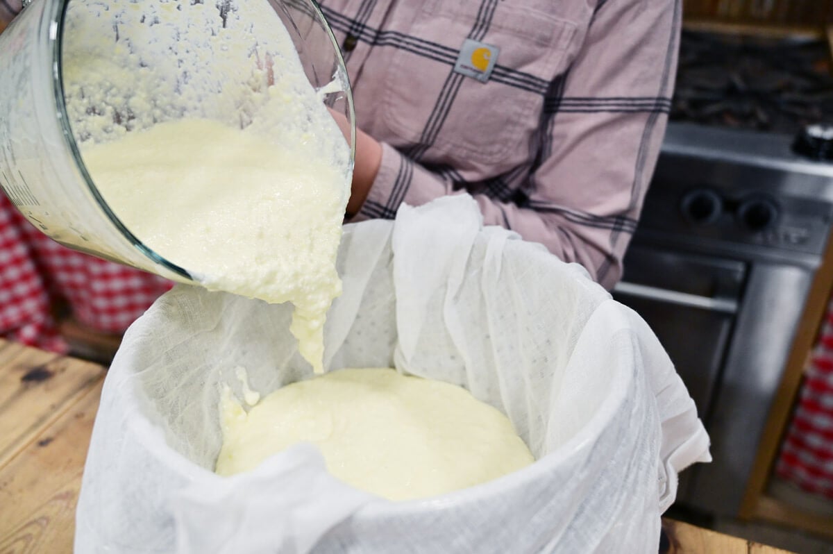 Yogurt being poured into a cheesecloth lined bowl to be strained.