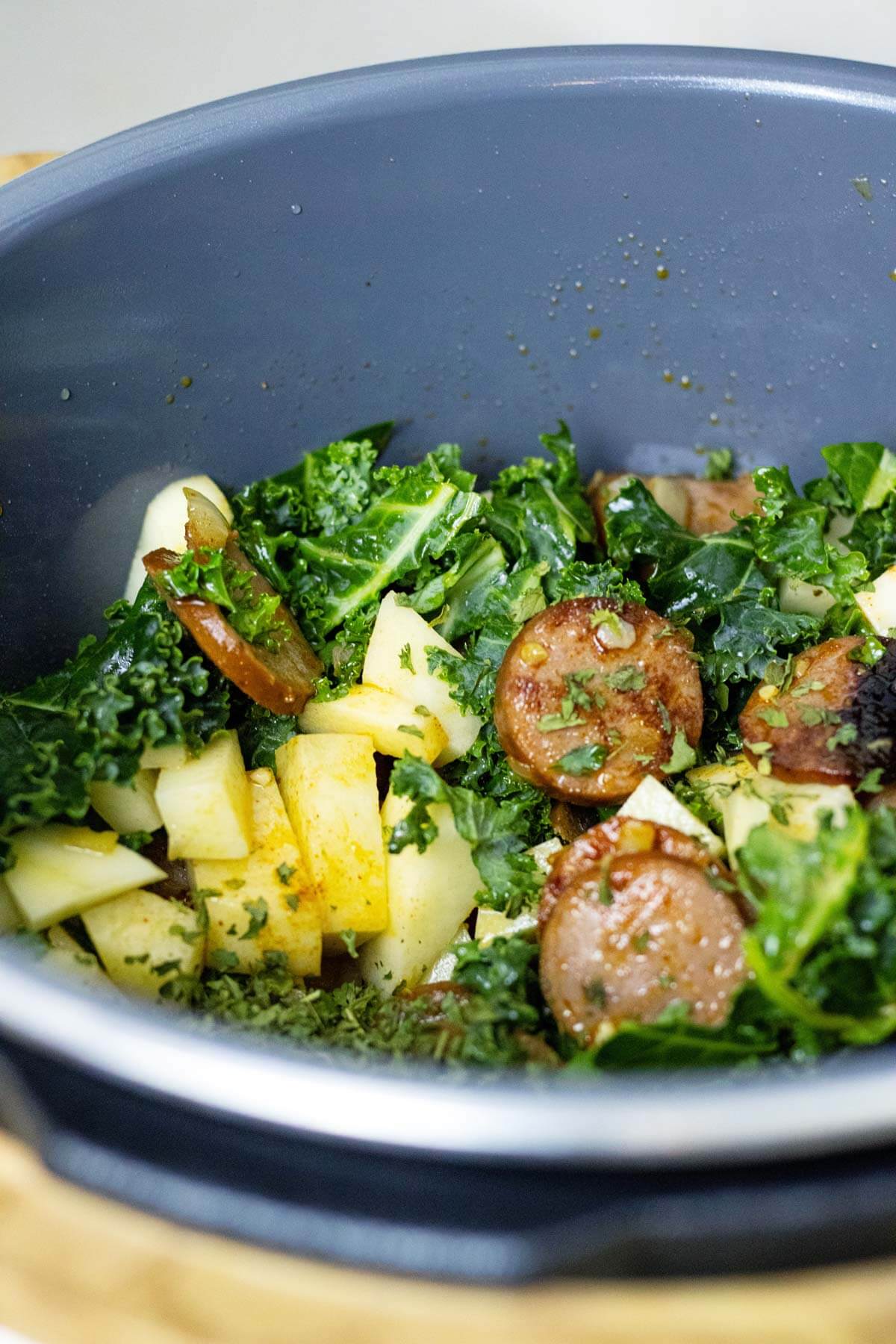 Sautéing kale with browned sausage and onions in the Instant Pot.