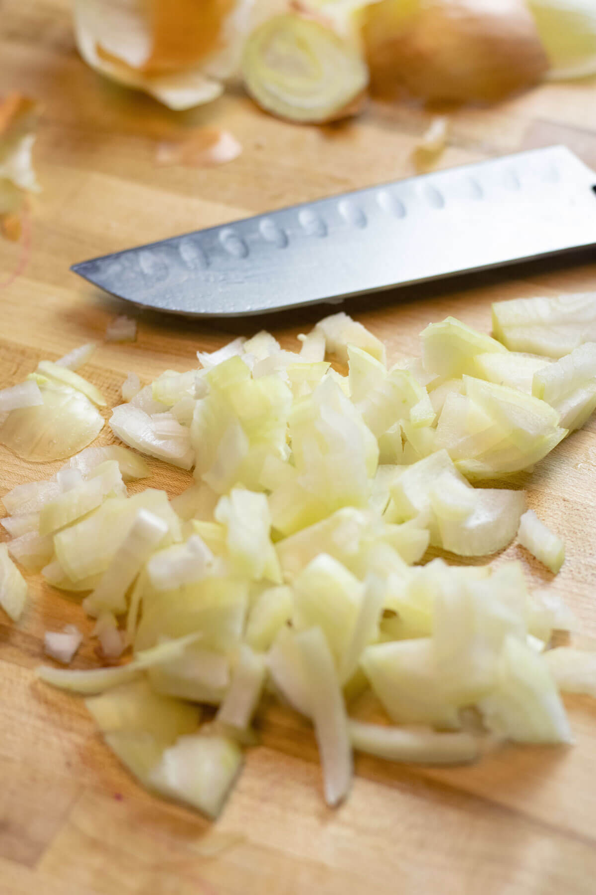 Chopped onions on a cutting board with a chef knife.
