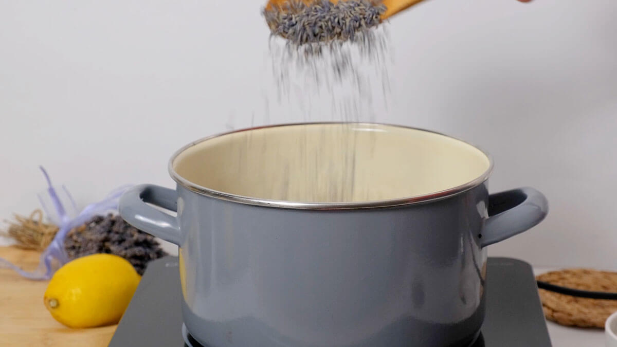 A spoon adding lavender to a saucepan.