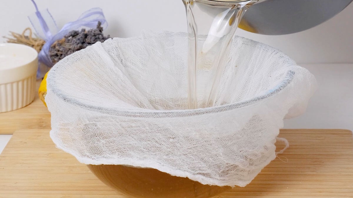 Straining lavender tea into a bowl through a cheesecloth.