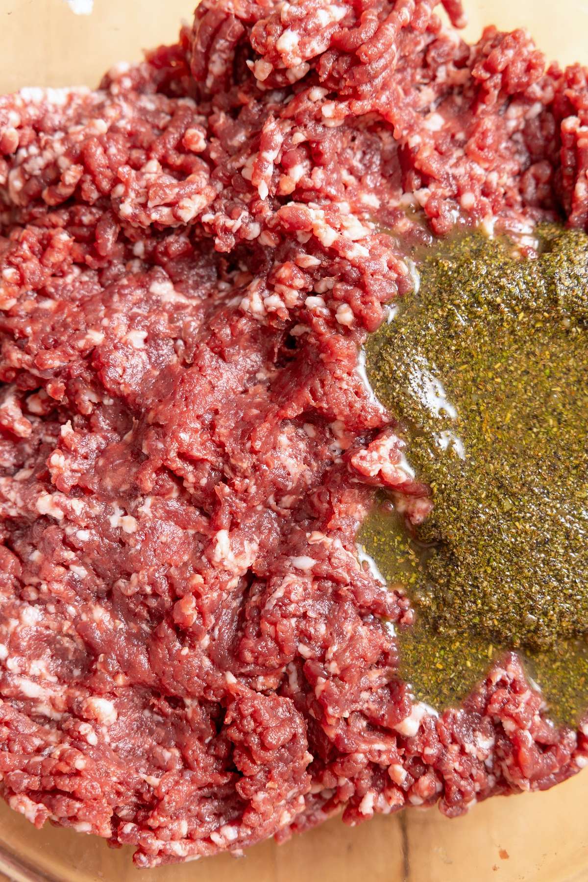 Ground wild game and pork fat with herb seasoning added to the bowl.