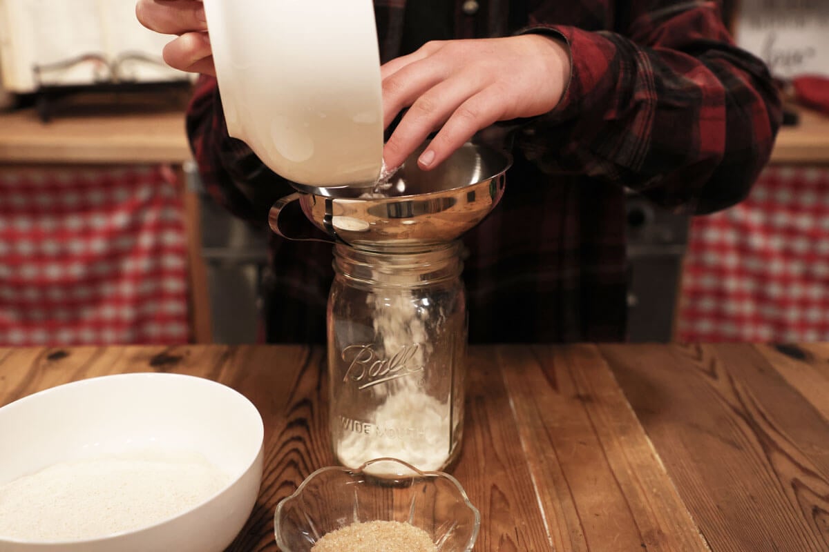 Flour being added to a Mason jar.