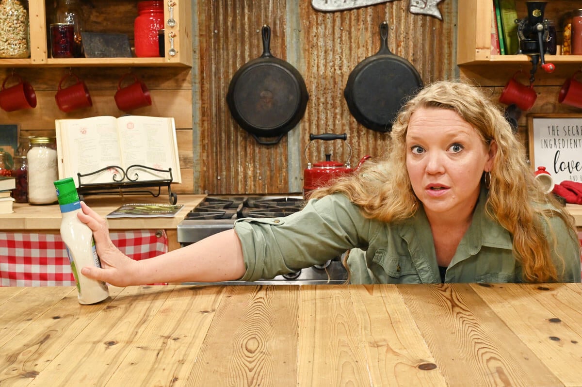 A woman pushing over a bottle of store-bought Hidden Valley ranch dressing.
