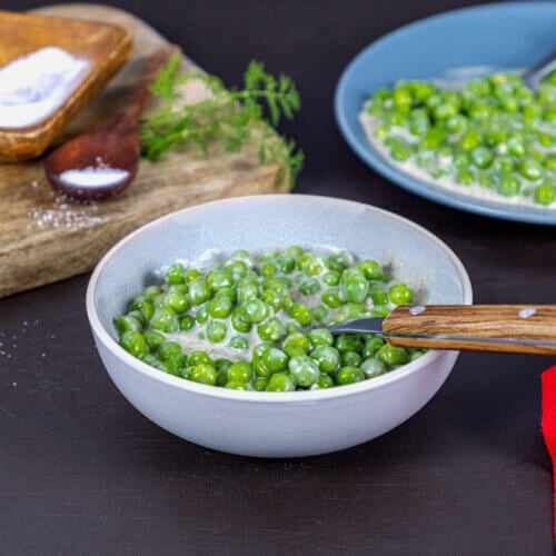 Cooked creamed peas served in a white bowl.