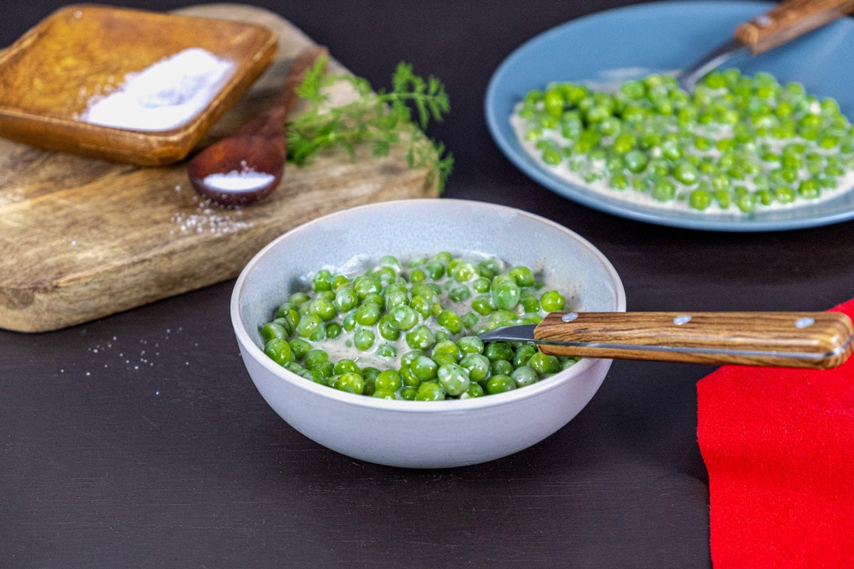 Cooked creamed peas served in a white bowl.