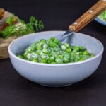Cooked creamed peas served in a white bowl.