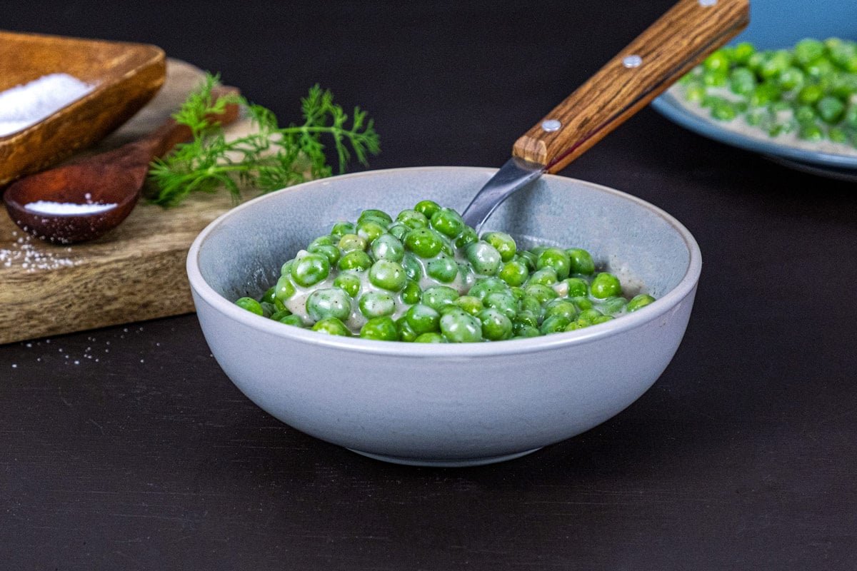 Cooked creamed peas served in a white bowl.
