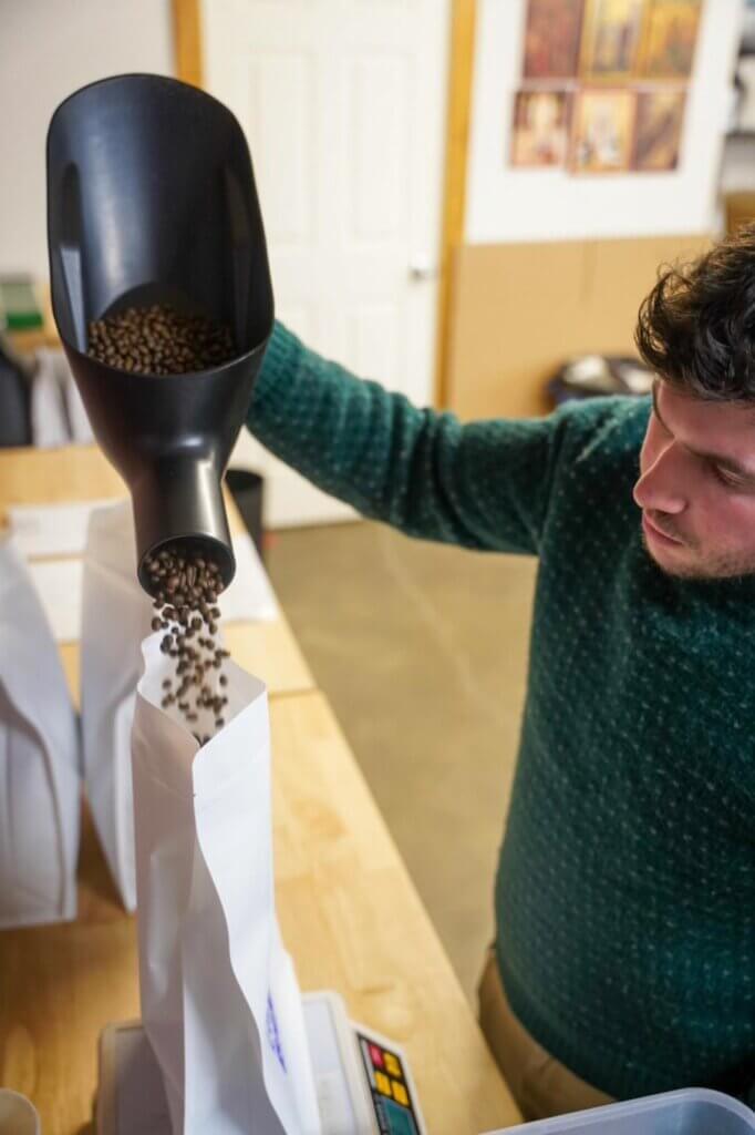 A man filling a bag with coffee beans.