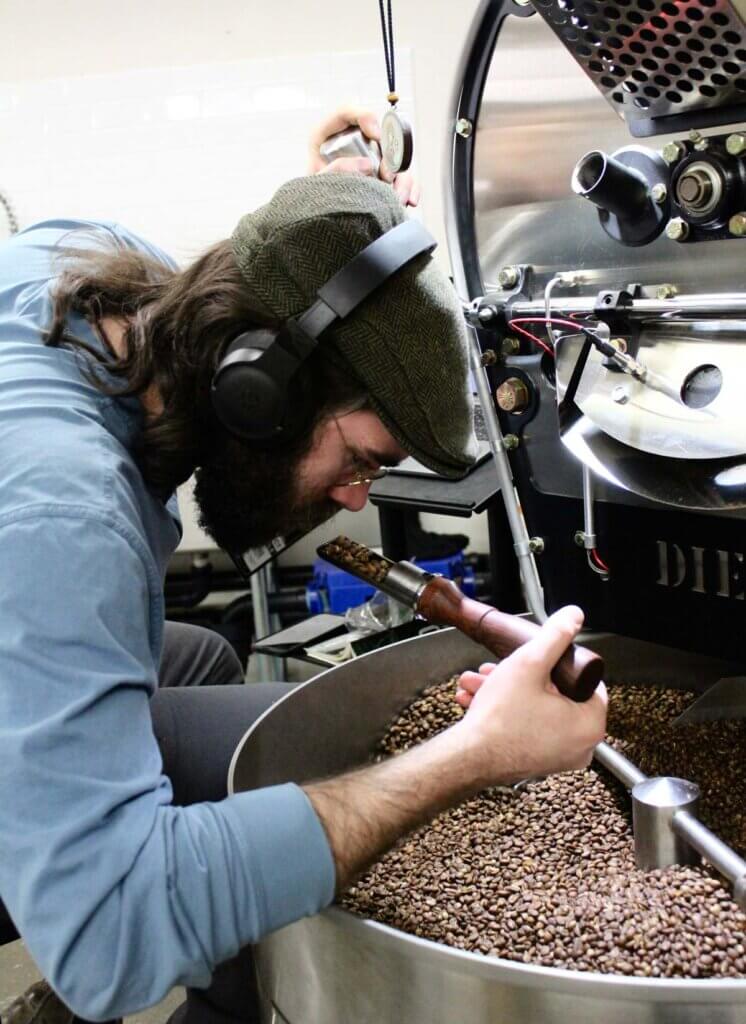A man smelling roasting coffee beans.