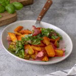 Roasted radishes and carrots on a plate garnished with fresh herbs.