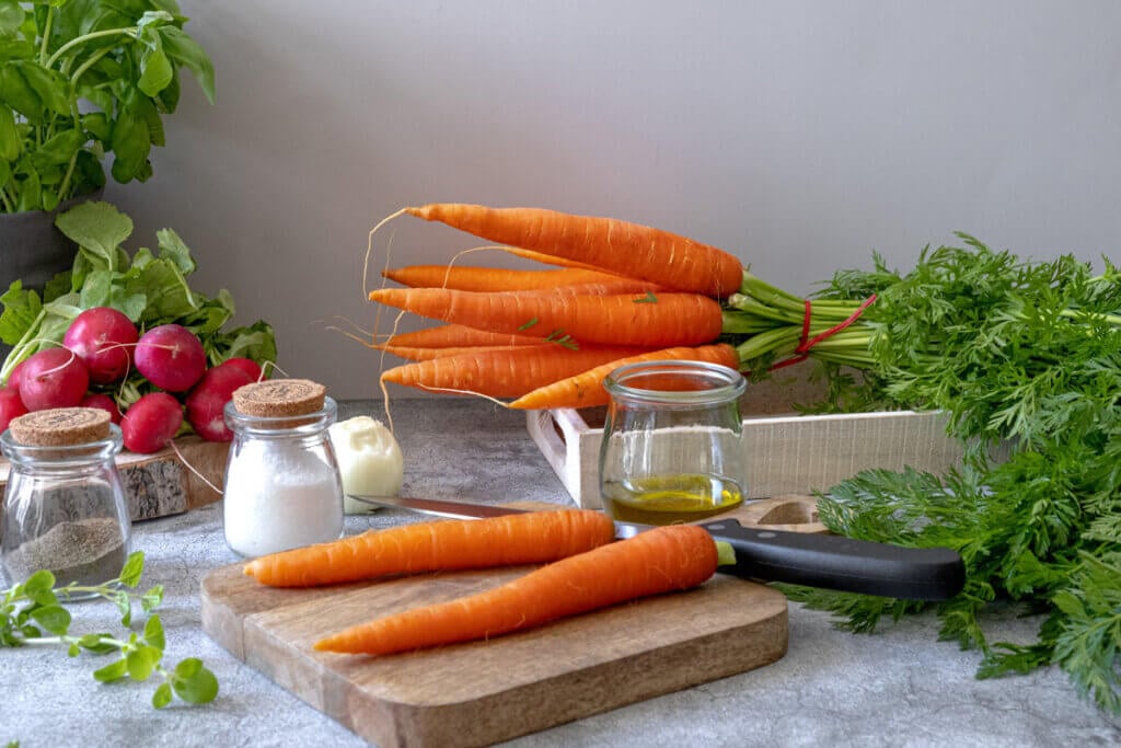 Whole carrots on a cutting board waiting to be chopped.