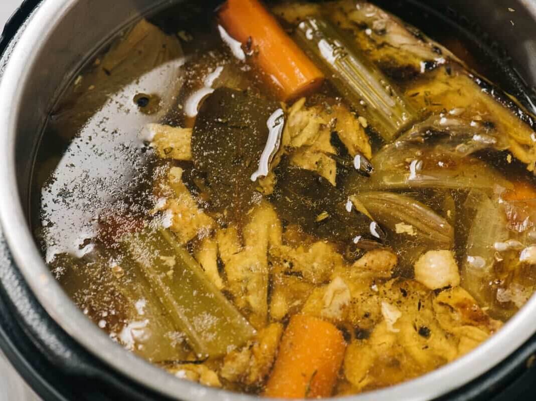 An Instant Pot filled with bone broth and ingredients.
