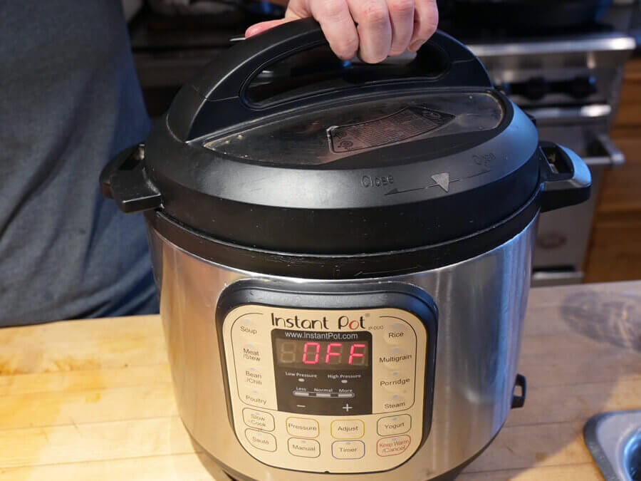 A hand putting the lid onto an Instant Pot.